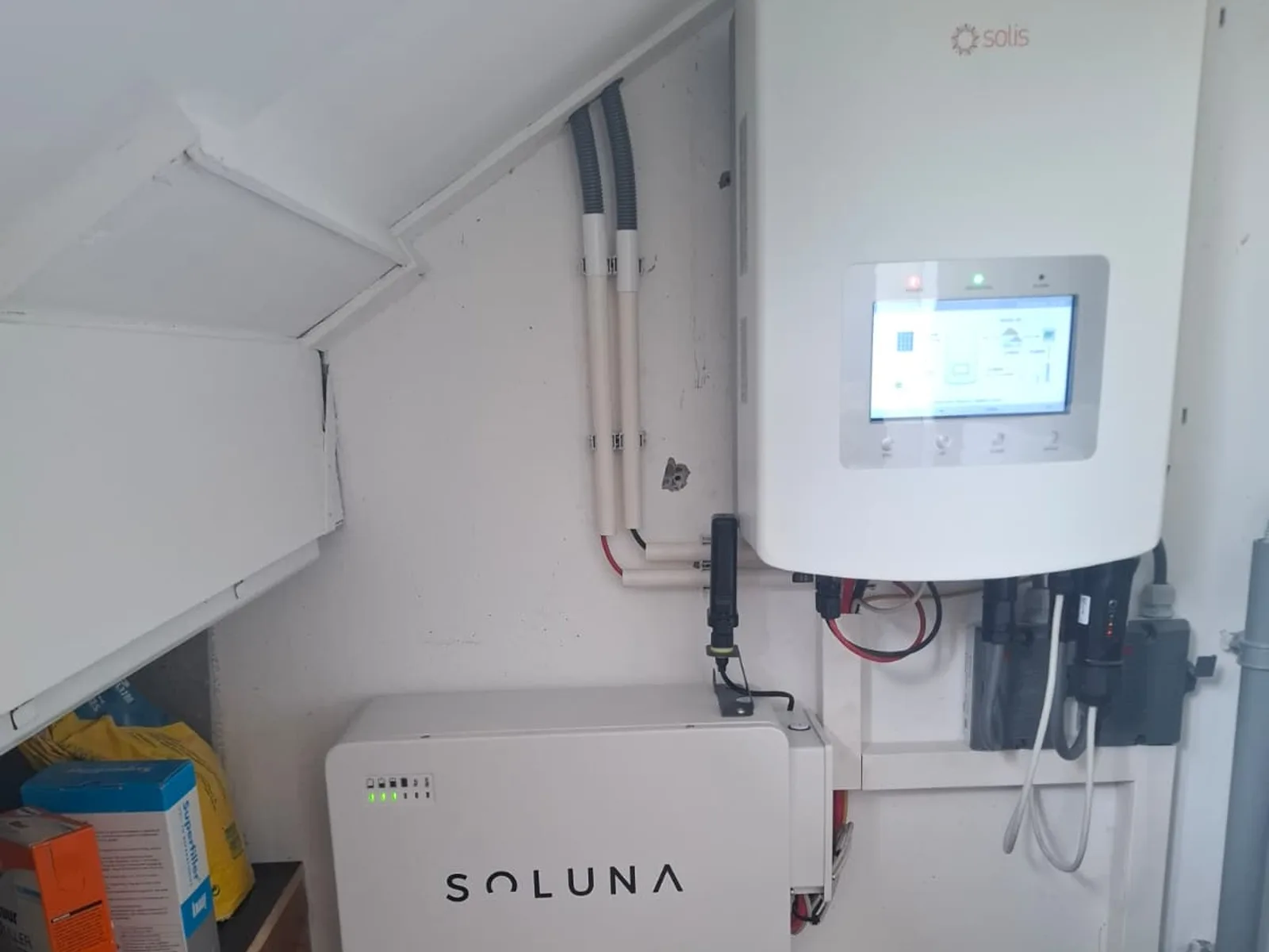 Solis hybride omvormer aan de wand met de Soluna batterij eronder in de bergruimte