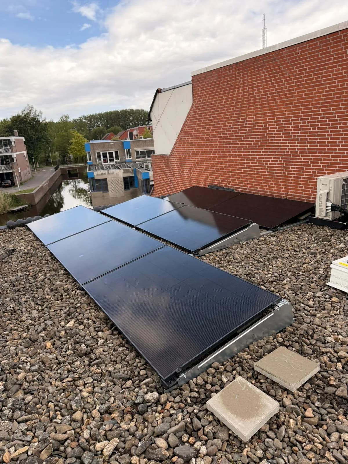 Rij zwarte zonnepanelen op het platte dak, gezien vanaf de gevel