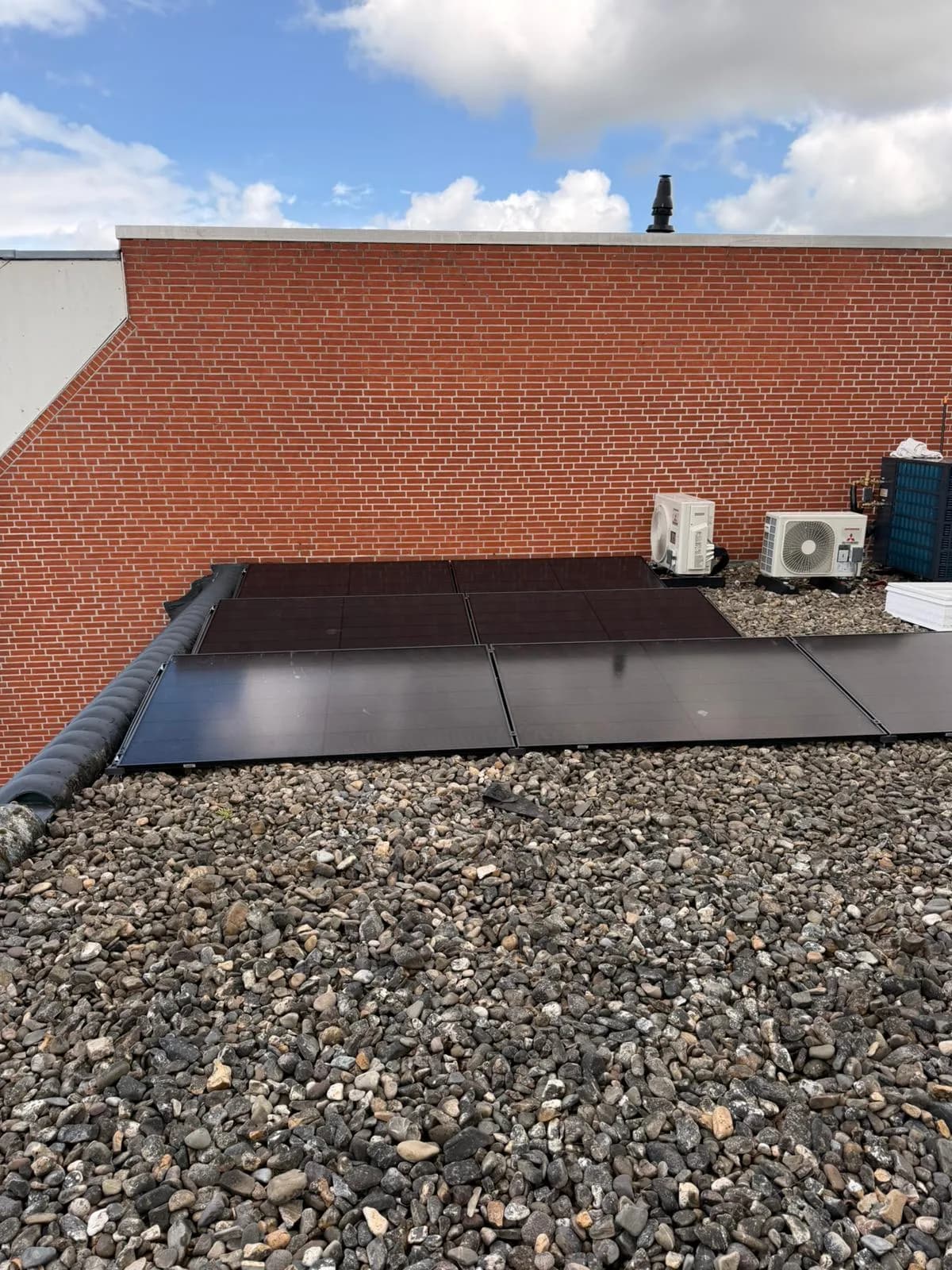 Plat dak met zonnepanelen en de buitenunit van een warmtepomp, aangelegd door Maatje Solar Systems